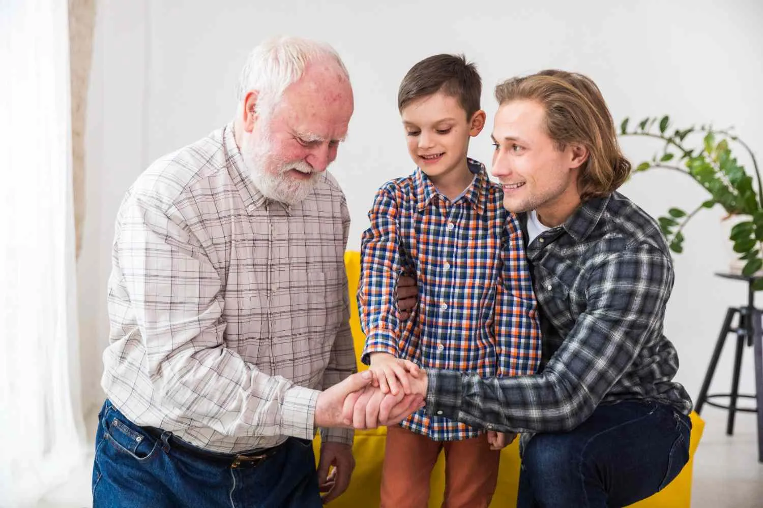 Grandfather, father and young son joining hands together at home